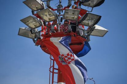 Un grupo de trabajadores coloca una bandera gigante en lo alto de una torre en el aeropuerto para recibir a la selección de fútbol croata. 