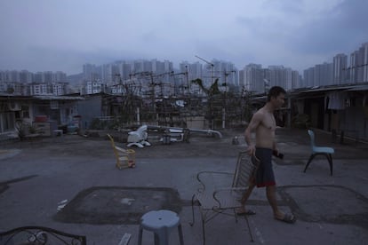 Un hombre en el exterior de su choza ilegal construída en una azotea, cerca de una urbanización pública.