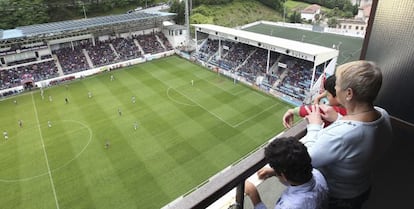 Una familia ve desde su vivienda un partido del &Eacute;ibar, en el estadio de Ipur&uacute;a, la temporada pasada. 