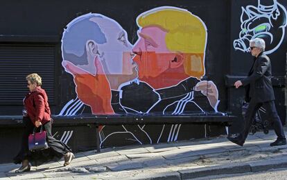 Gente paseando ante un mural en el que aparece el Presidente electo Donald Trump y el Presidente ruso Vladimir Putin 