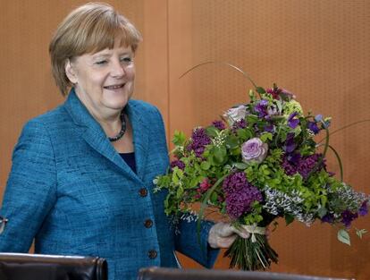 Angela Merkel con una ramo de flores para el secretario de Presidencia, por su cumpleaños.