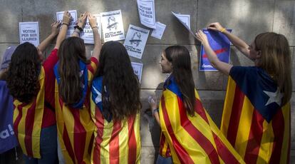 Varias estudiantes ponen carteles por el referéndum del 1 de octubre en la pared de la Universidad de Barcelona.