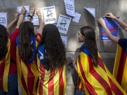 Varias estudiantes ponen carteles por el referéndum del 1 de octubre en la pared de la Universidad de Barcelona.