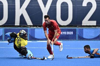 El español David Alegre regatea la pelota entre el portero indio Sreejesh Parattu Raveendran y el jugador Harmanpreet Singh durante su partido del grupo A masculino de la competición de hockey sobre hierba de los Juegos Olímpicos de Tokio 2020.