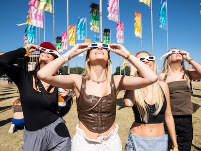 Mujeres observan el eclipse solar del 14 de octubre de 2023 en un festival de música en Austin.