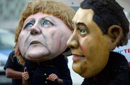 Protesta contra la injusticia social con máscaras Merkel y Sigmar Gabriel, del SPD, en la segunda ronda de negociaciones en Berlín.