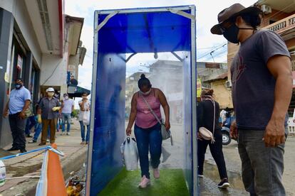 Una mujer pasa por un túnel desinfectante en Daule, en la provincia de Guayas (Ecuador). Daule, uno de los cantones más afectados por el coronavirus, ha sido el primero de Ecuador que ha cambiado su "semáforo epidemiológico" de rojo a amarillo, con lo cual ha permitido ciertas actividades comerciales y hasta el transporte municipal hasta las 18.00.