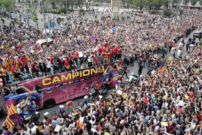 Una multitud de seguidores del Barcelona aclama a los jugadores subidos al autocar descapotable en el que se pasearon por las calles de la ciudad.
