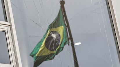 Una bandera de Brasil se refleja en una ventana rota tras el asalto al palacio de Planalto.