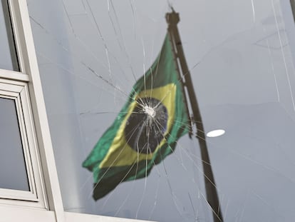 Una bandera de Brasil se refleja en una ventana rota tras el asalto al palacio de Planalto.