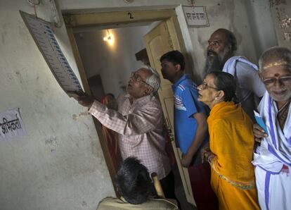 Votantes miran una pancarte antes de votar en Varanasi (India).