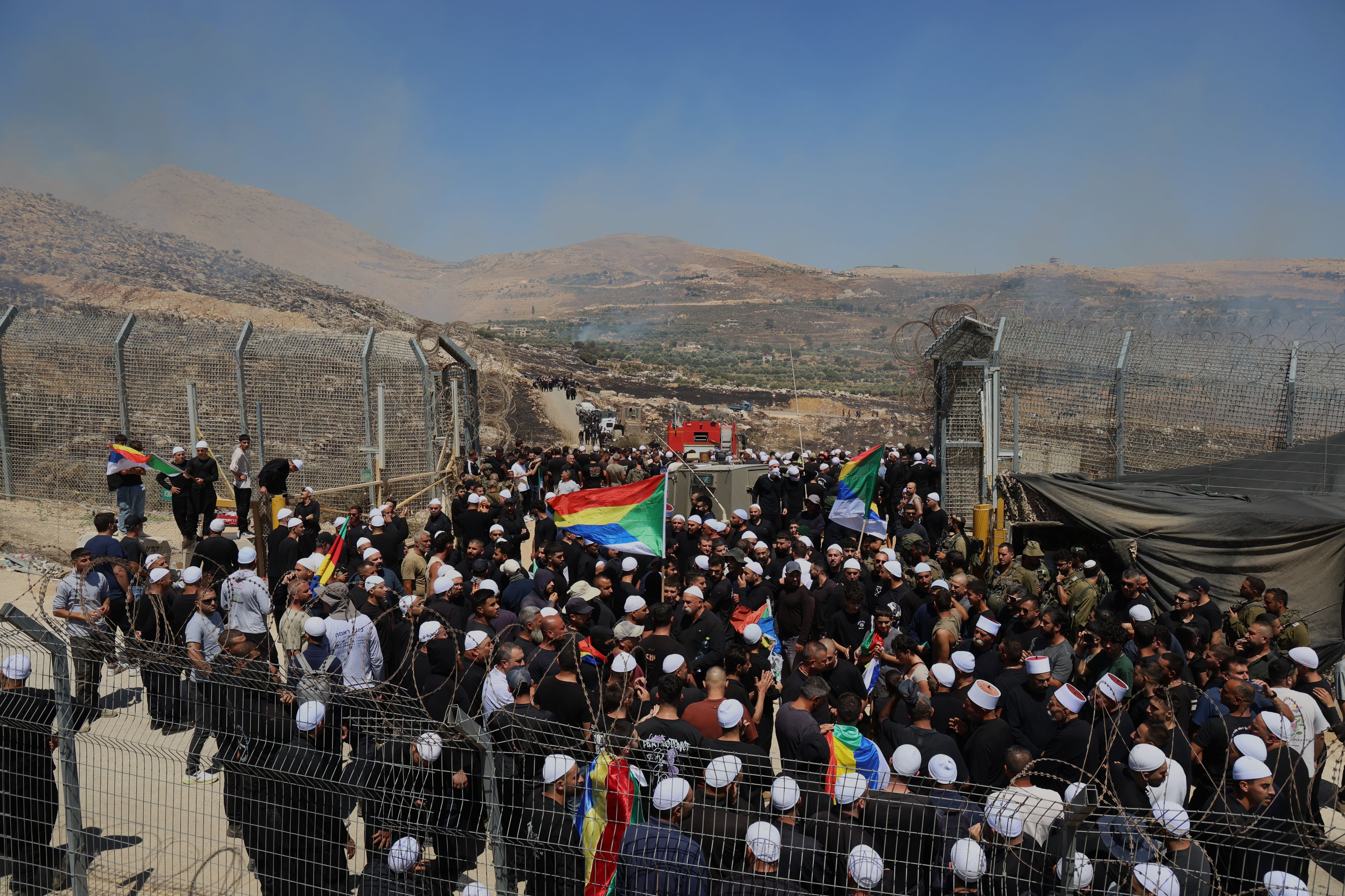 Cientos de personas se agolpan con la bandera drusa en Majdal Shams, bajo ocupación israelí, para pasar al otro lado de la valla que les separa de la Siria administrada por Damasco.