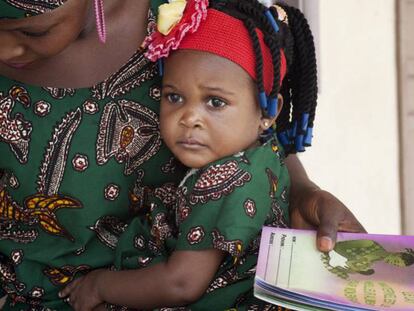 Belvine, de Benín, espera con su madre la visita a la enfermera para el control mensual del tratamiento preventivo de tuberculosis.