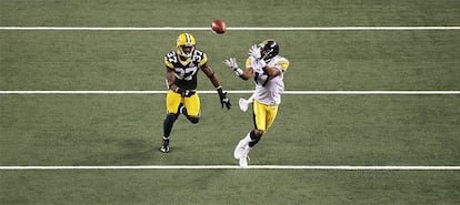 Mike Wallace, suspendido en el aire, se dispone a recibir el balón ante la atenta mirada de un jugador de los Packers.