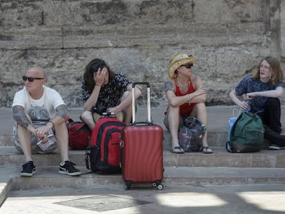 Un grupo de turistas descansan junto a las Torres de Serranos, en Valencia. 