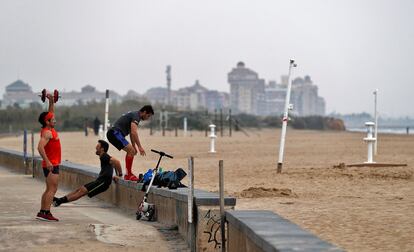 Tres hombres practican deporte en una playa de Valencia, este domingo.