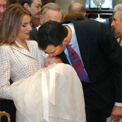 El príncipe Felipe besa a su hija, la infanta Leonor, que descansa en brazos de su madre, la princesa Letizia, durante el bautizo oficiado este mediodía por el arzobispo de Madrid, el cardenal Antonio María Rouco Varela, en la ceremonia religiosa celebrada en el vestíbulo del Palacio de la Zarzuela.