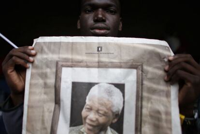 Un sudafricano sostiene una fotografía de difunto presidente sudafricano Nelson Mandela en el interior del Estadio Orlando en Soweto.