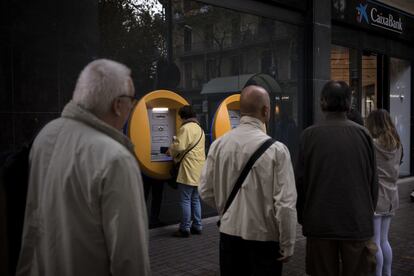 Esta iniciativa llamaba a retirar la cantidad que el consumidor quisiera, preferentemente entre las ocho y las nueve de la mañana, y a destinar el dinero a la compra semanal, a hacer un donativo a una ONG o al consumo propio. En la imagen, un grupo de personas espera junto a un cajero de CaixaBank, en Barcelona.