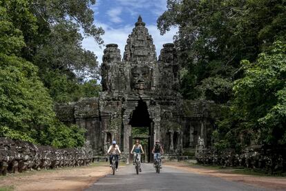 Un grupo de turistas recorre el enorme complejo de Angkor en bicicleta.