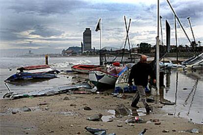 Un hombre observaba ayer los desperfectos causados por el temporal en la playa del Port Olímpic de Barcelona.