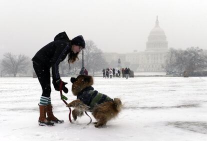 Una chica juega con su perro en un parque nevado cerca del Capitol en Washington.