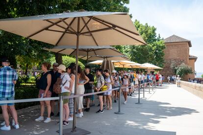 Una fila de personas esperan bajo sombrillas para entrar en la Alhambra de Granada, el martes. 
