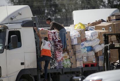 Trabajadores de la Media Luna Roja se suben a uno de los camiones con ayuda humanitaria que han cruzado la frontera egipcia de Rafah, este sábado en Gaza. 