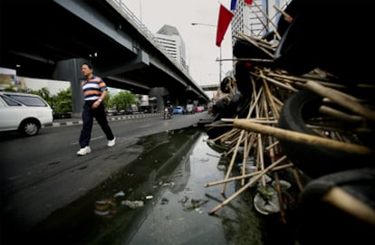 Un hombre bordea las empalizadas que limitan el campamento de los <i>camisas rojas</i> en el corazón financiero de Bangkok.