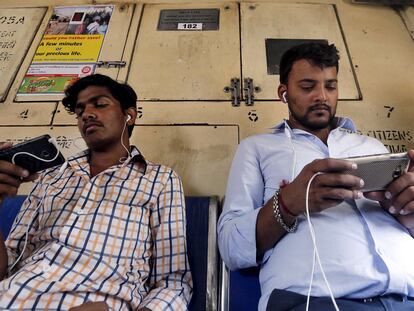 Dos viajeros usan sus teléfonos móviles en el metro de Bombay, India.