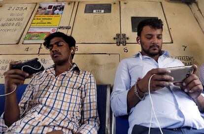 Dos viajeros usan sus teléfonos móviles en el metro de Bombay, India.