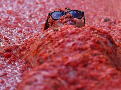 Uno de los participantes en la Tomatina 2014 se reboza en el suelo en tomate triturado.