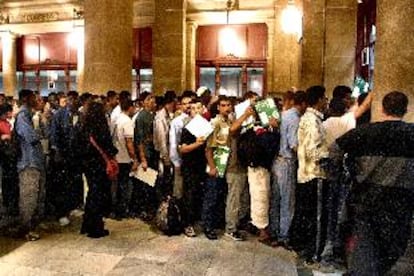 Decenas de inmigrantes, mayoritariamente magrebíes, haciendo cola ayer en la oficina de Correos de la plaza de Antoni López de Barcelona.