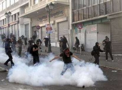 Un grupo de manifestantes entre el humo de los botes lanzados por la policía durante los choques violentos entre manifestantes y las fuerzas de seguridad durante una huelga general de 24 horas en Grecia. EFE/Archivo