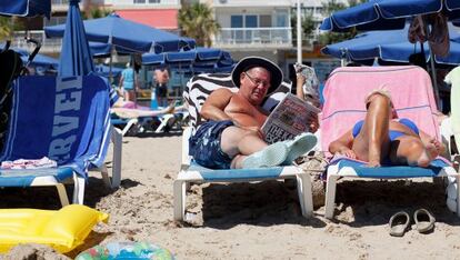 Un hombre lee un diario británico en una playa de Benidorm