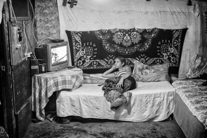 Una joven mujer pasa el tiempo mirando la televisión en el interior de su chabola.