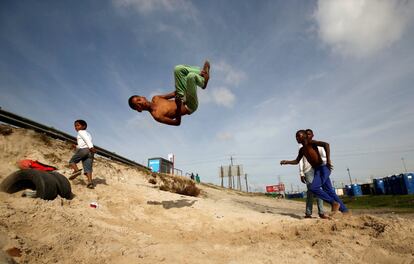Varios jóvenes saltan sobre neumáticos viejos en el municipio de Khayelitsha, en Sudáfrica.