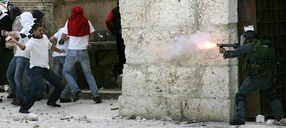 Varios palestinos tiran piedras a un policía israelí a las puertas del templo de Al Aqsa, en la Explanada de las Mezquitas en Jerusalén.
