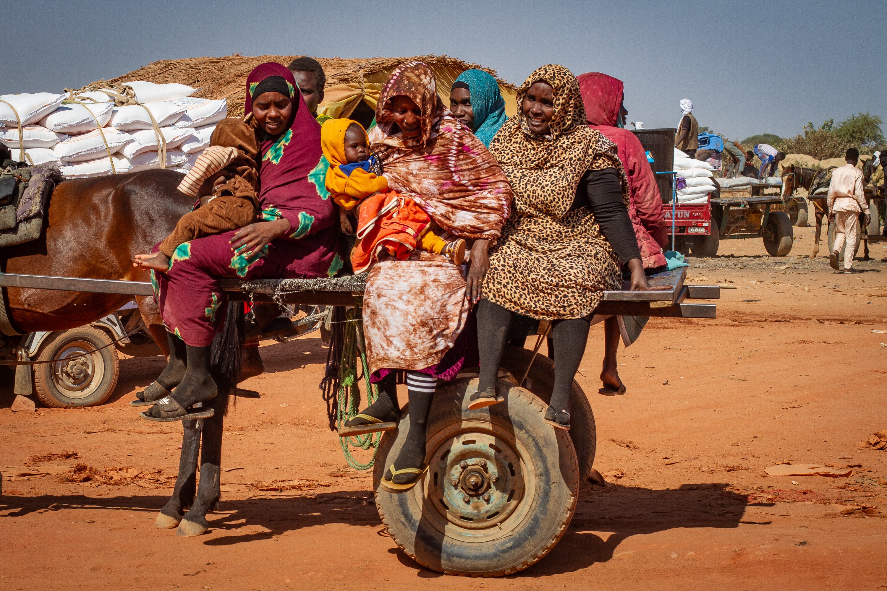 Un grupo de mujeres sudanesas con niños llega en carretilla a Adré, primera población chadiana tras cruzar la frontera de Sudán con este país, en diciembre de 2025.