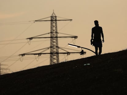 Un peatón camina frente a las torres de electricidad de alto voltaje en Hamburgo, Alemania, en agosto de 2022.