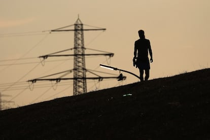 Un hombre camina cerca de una torre eléctrica en Hamburgo (Alemania), el 24 de agosto.