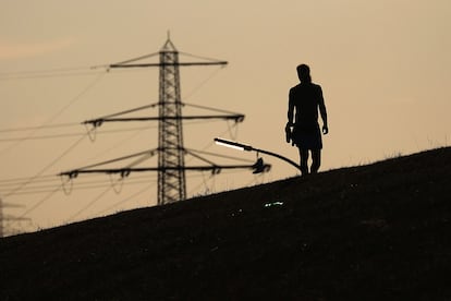 Un peatón camina frente a las torres de electricidad de alto voltaje en Hamburgo, Alemania, en agosto de 2022.