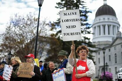 Una mujer sostiene una pancarta con el mensaje “Maine Lobsters Need Tourists” (Las langostas de Maine necesitan turistas” en una manifestación anticonfinamiento en Augusta, Maine (Estados Unidos).
