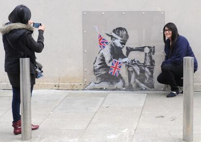 Dos turistas se fotograf&iacute;an con &#039;Slave Labour&#039;, el supuesto &#039;banksy&#039;, antes de que fuera arrancado para ser vendido.