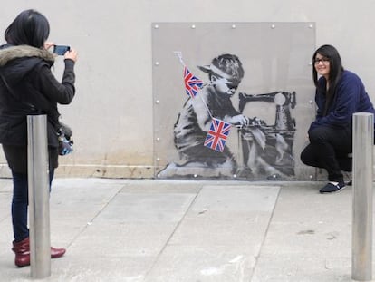 Dos turistas se fotograf&iacute;an con &#039;Slave Labour&#039;, el supuesto &#039;banksy&#039;, antes de que fuera arrancado para ser vendido.