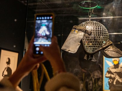 'Met ball', casco de policía antidisturbios con cristales, de Banksy. Y atrás, 'Flying Copper'. Las dos se pueden ver en la exposición del Disseny Hub Barceona.