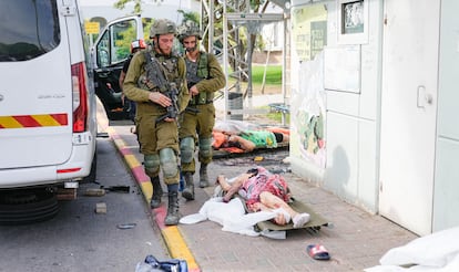 Israeli soldiers walk past bodies of victims of the October 7, 2023 attacks in Sderot, southern Israel.