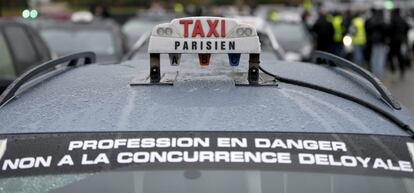 El cartel &quot;La profesi&oacute;n est&aacute; en peligro. No a la competencia desleal&quot; colocado en el parabrisas de un taxi durante el paro convocado por el sector en Par&iacute;s contra la plataforma Uber.