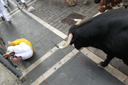Un mozo cae y queda expuesto a los cuernos de un toro de la ganadería sevillana de Dolores Aguirre durante el tercer encierro de San Fermín.