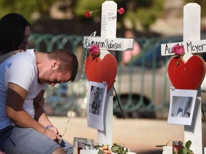 Amigos de una de las víctimas de la matanza de Las Vegas, junto a una cruz en su honor.